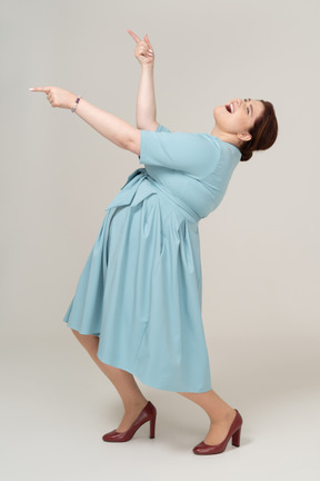 Счастливая женщина в синем платье танцует