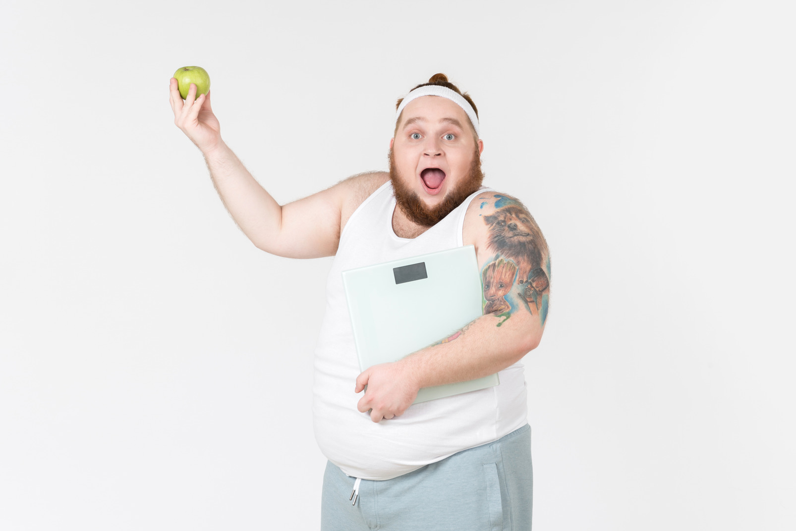 Excited young big guy in sportswear holding digital weights and apple