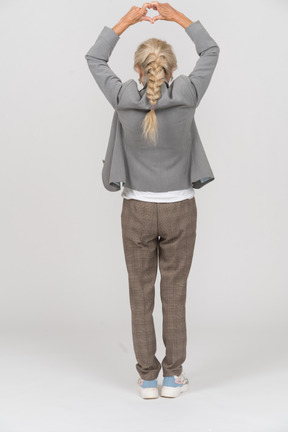 Rear view of an old lady in suit making heart sign with her fingers