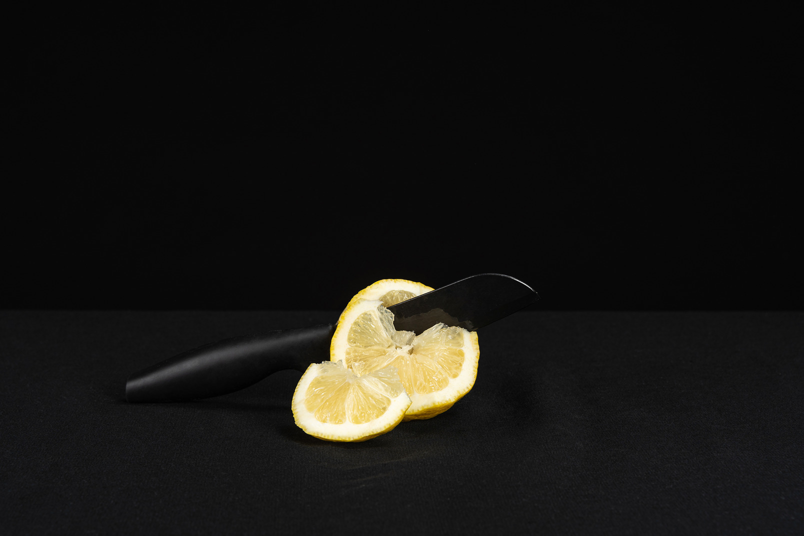 Knife cutting lemon in black background
