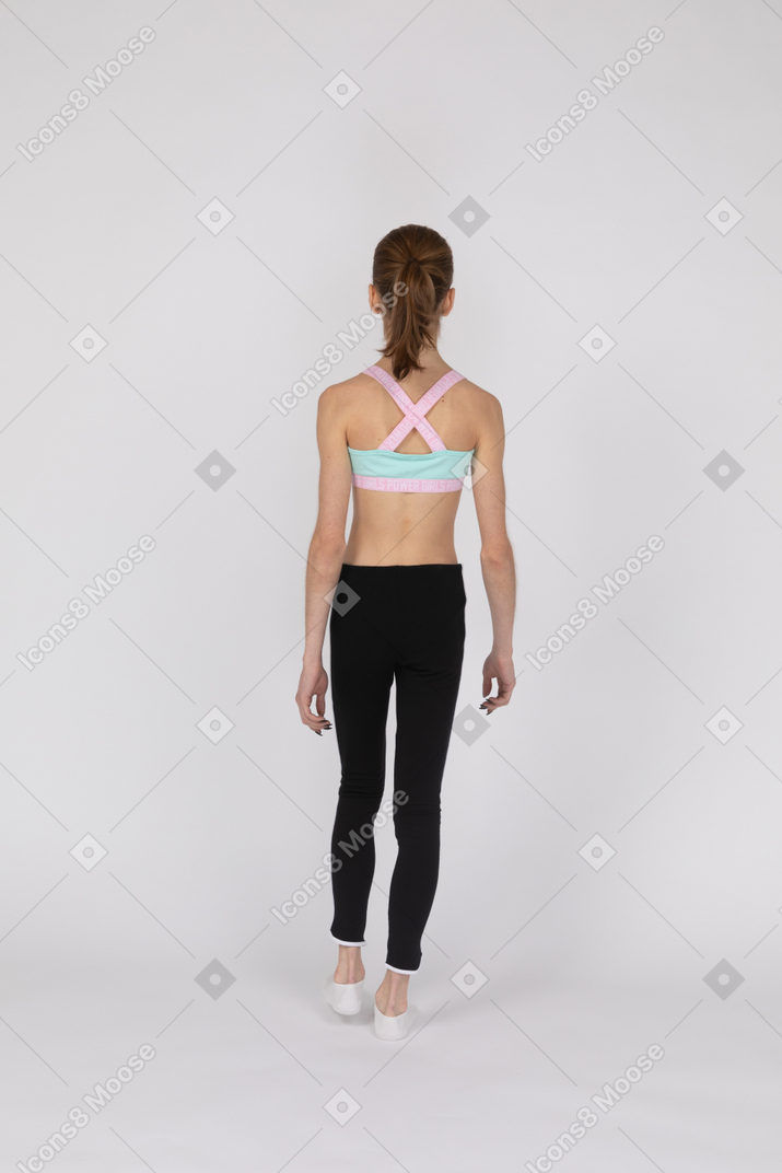 Vista posterior de una jovencita en ropa deportiva caminando