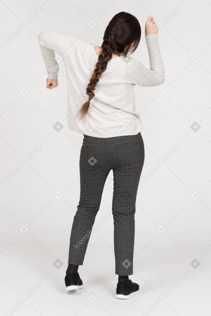 Mulher com cabelos castanhos compridos dançando de volta para a câmera