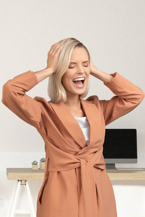 A woman with blonde hair is smiling and holding her hands behind her head