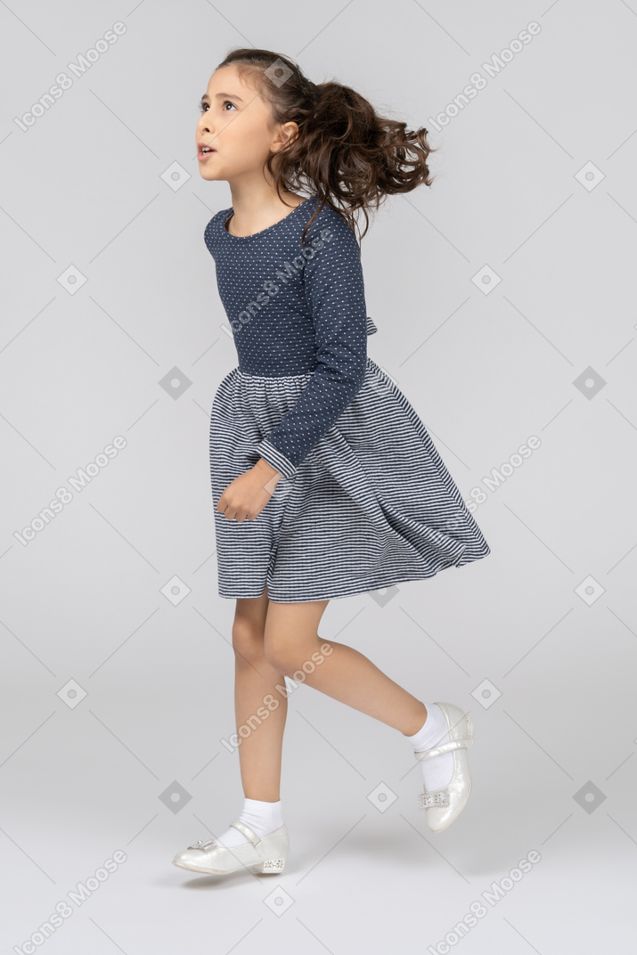 Vista de tres cuartos de una niña corriendo en movimiento