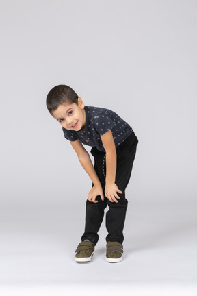 Front view of a happy boy bending down and looking at camera