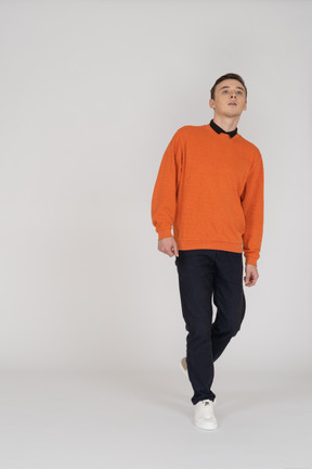 オレンジ色のスウェットシャツを歩いている若い男