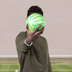 A man holding a ball in front of his face