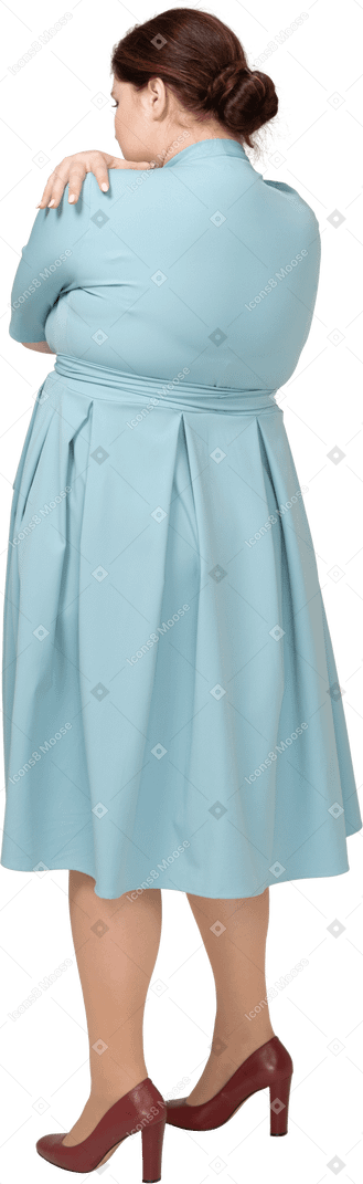 一个穿着蓝色连衣裙的女人拥抱自己的后视图