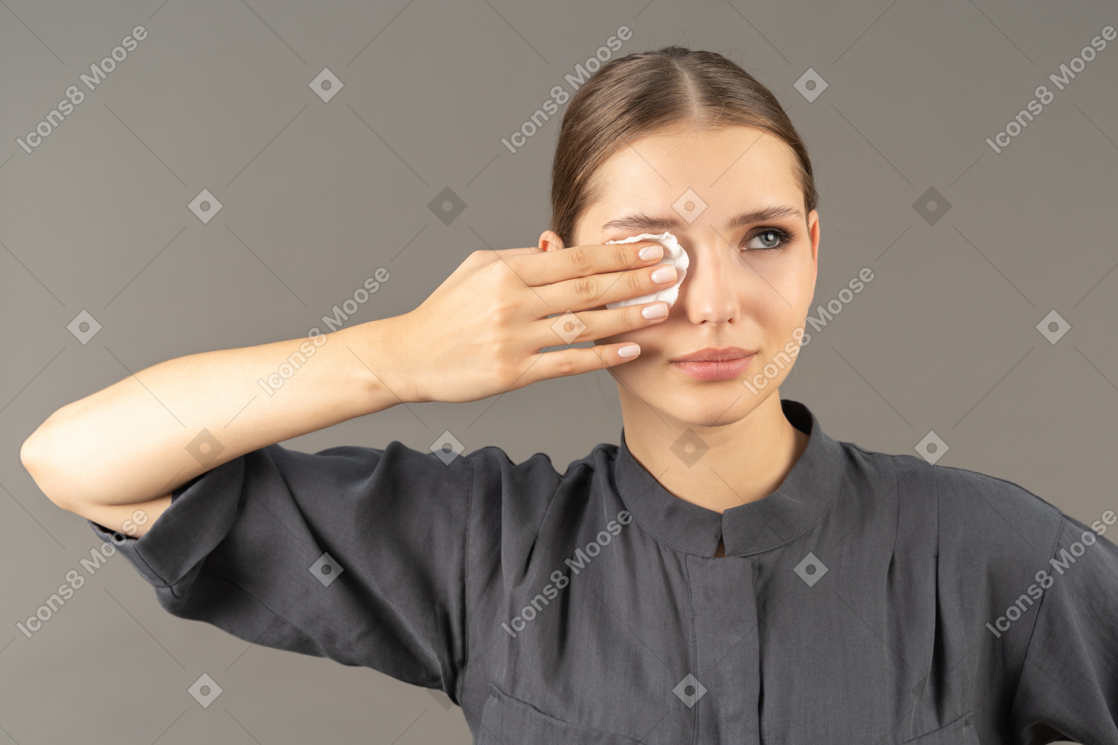 Вид спереди молодой женщины в комбинезоне, снимающей макияж с глаз