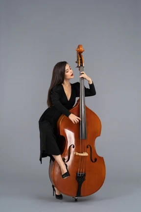 Front view of a young woman in black dress playing her double-bass putting leg on it