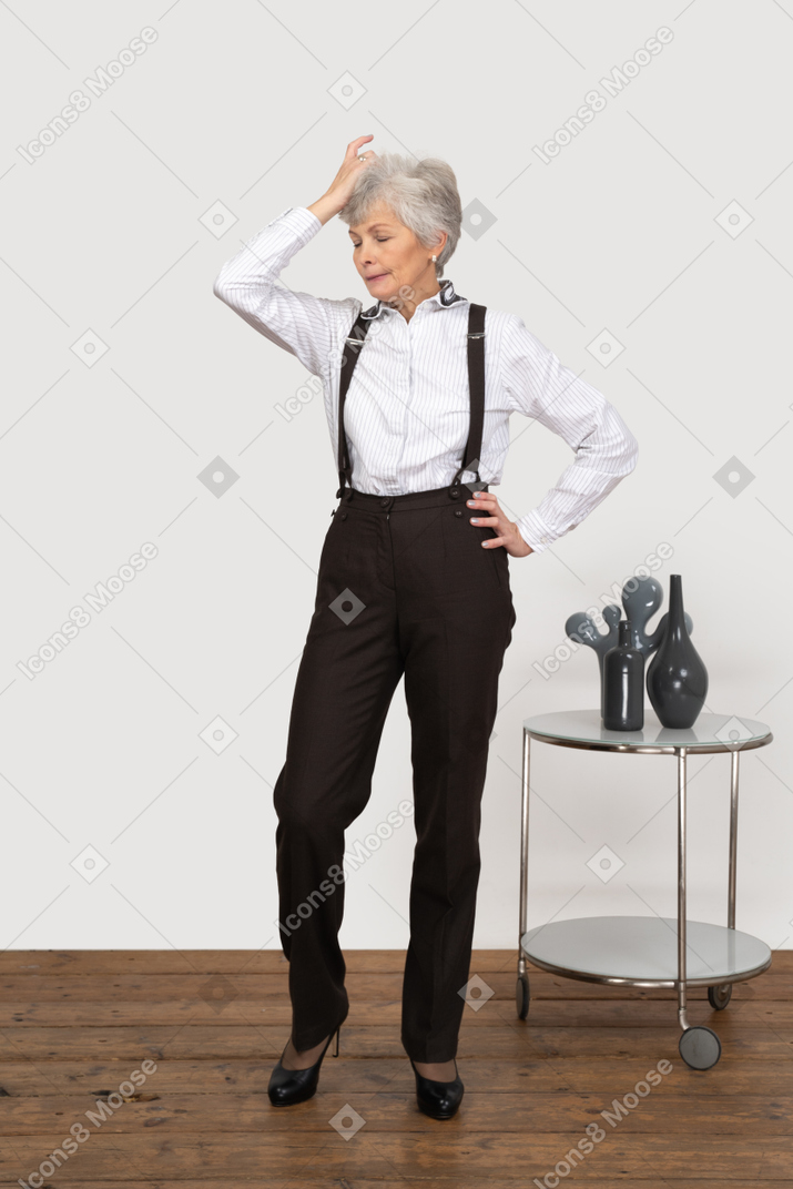 一个健忘的老太太在摸她的头的办公服装的前视图