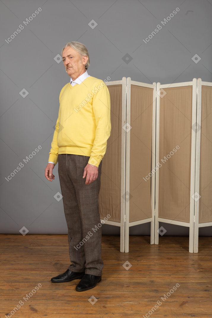 Vista de tres cuartos de un anciano inmóvil mirando a la cámara