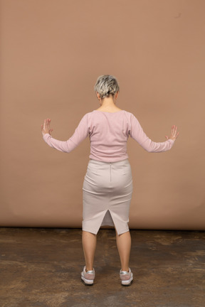 Вид сзади женщины в повседневной одежде, показывающей размер чего-то