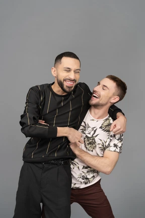 Dos jóvenes hombres caucásicos abrazándose y riendo felizmente