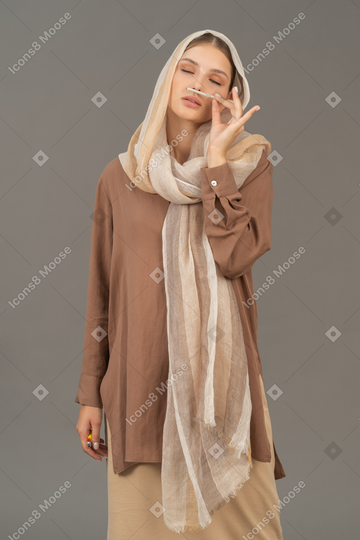 Woman in beige clothes enjoying the smell of cigarette