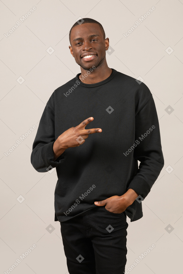 Smiling young man showing peace sign