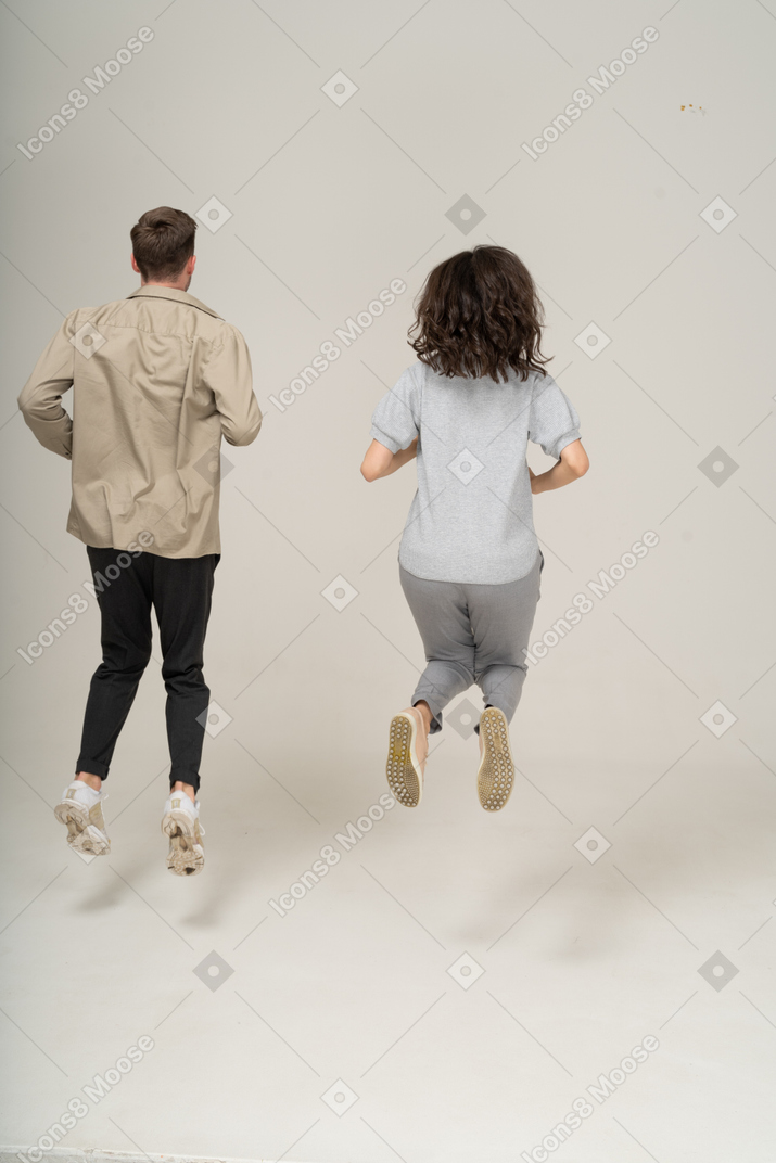 Back view of young man and woman jumping