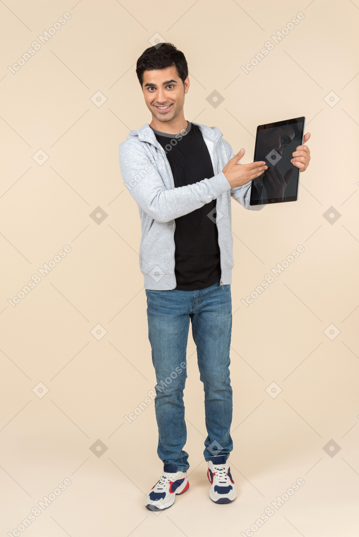 Giovane uomo caucasico che punta a una tavoletta digitale che sta tenendo