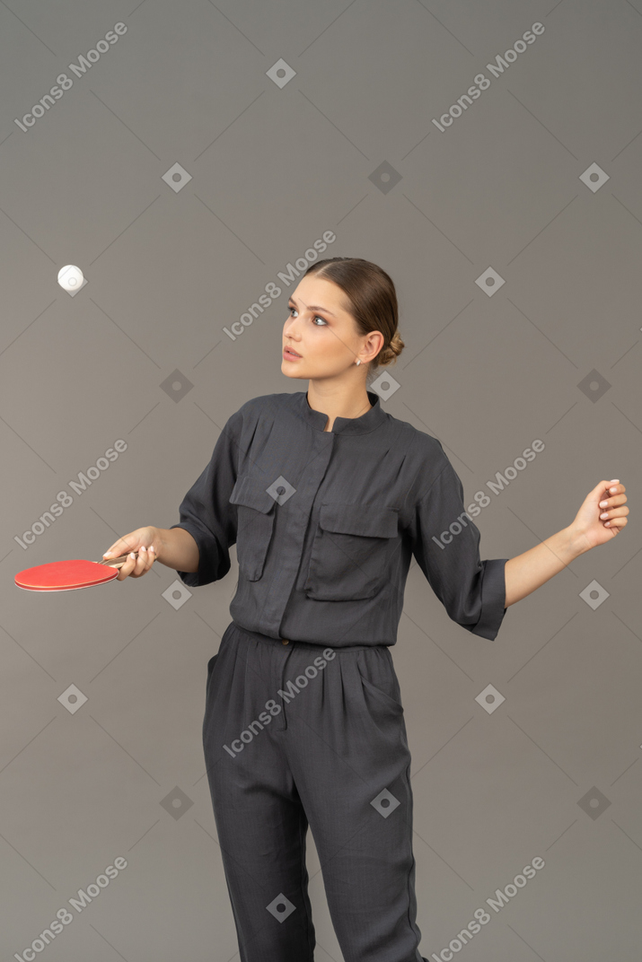 Front view of young woman in a jumpsuit playing table tennis