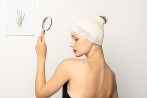 Young woman with bandaged head holding up magnifier