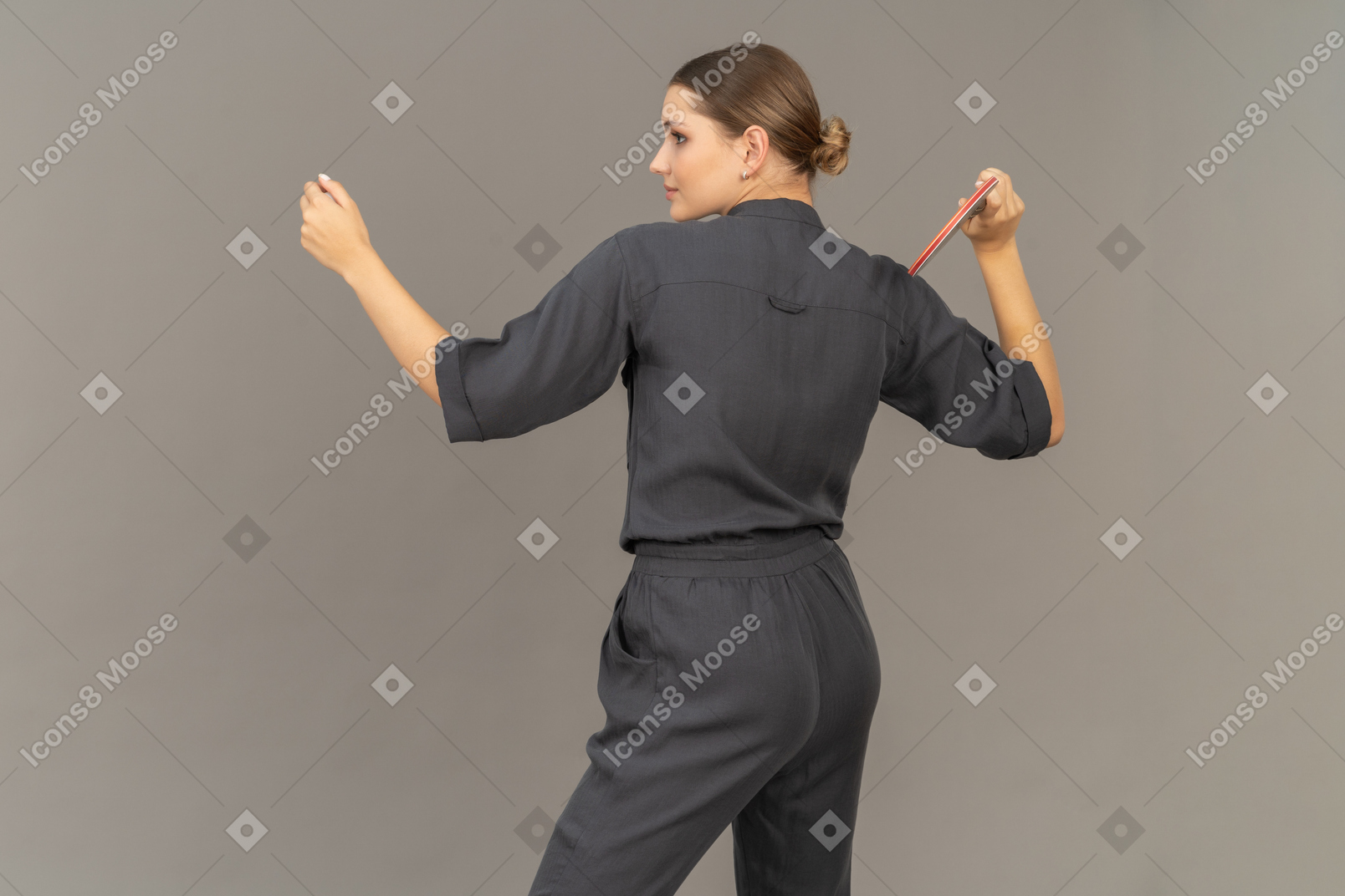 Three-quarter back view of young woman in a jumpsuit playing table tennis
