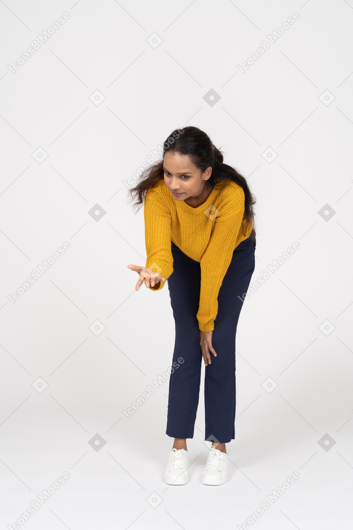 Front view of a girl in casual clothes bending down with extended arm