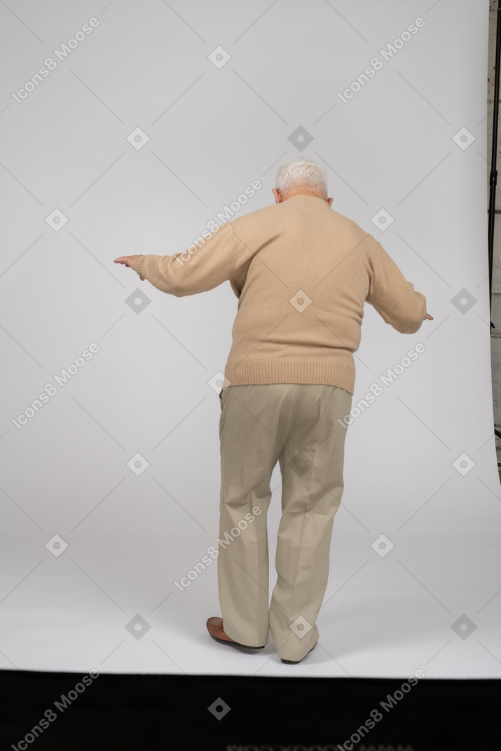 Vue arrière d'un vieil homme en vêtements décontractés en équilibre sur une jambe