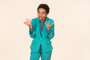 Black woman with a short haircut, wearing all blue, standing against a plain pastel background, looking emotional