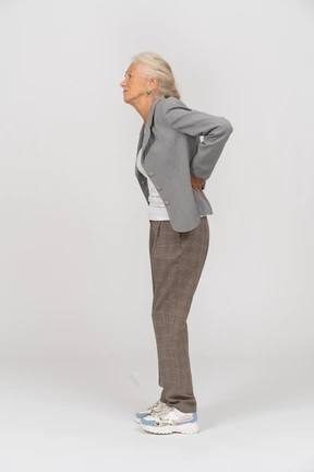 Side view of an old lady in suit suffering from pain in back
