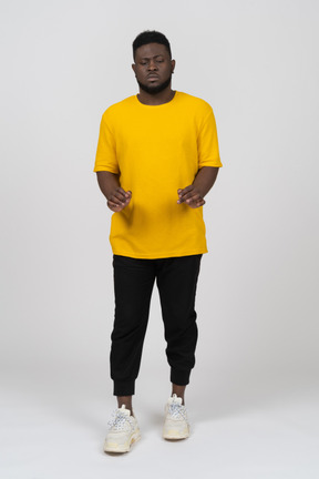 Front view of a young dark-skinned man in yellow t-shirt outstretching his arms  dow