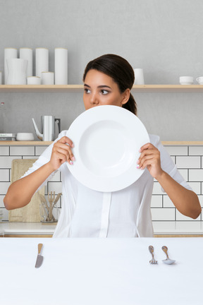A woman holding a plate in front of her face