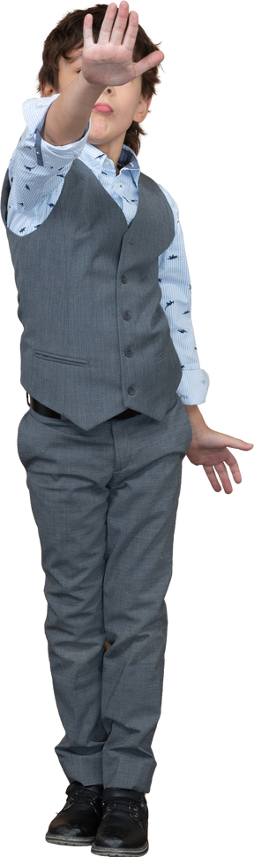 Front view of a boy in grey suit making stop gesture