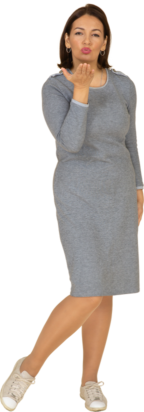 Vista frontal de uma mulher de vestido cinza mandando um beijo