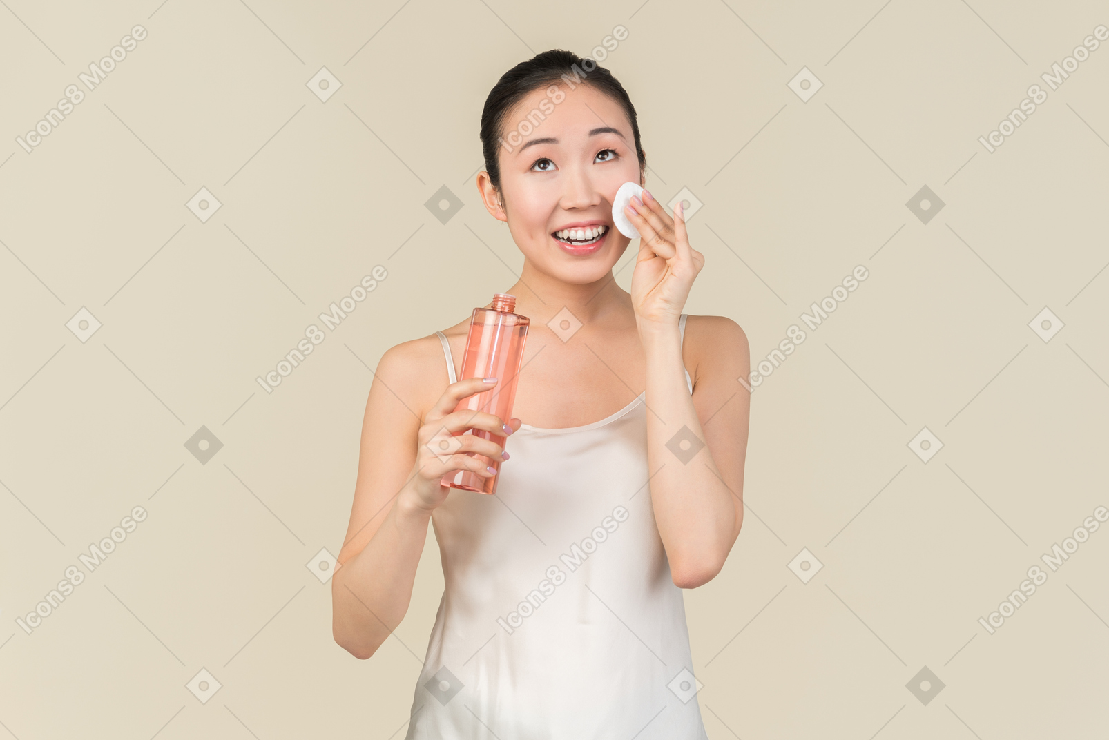 Smiling young asian woman holding applying cosmetic product on face skin
