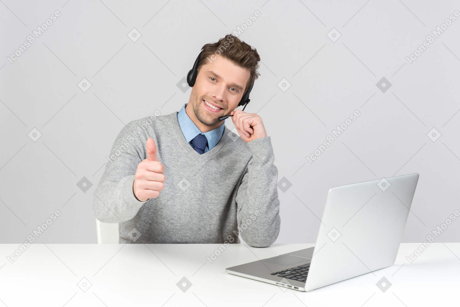 Call center agent sitting at the office desk and showing thumb up