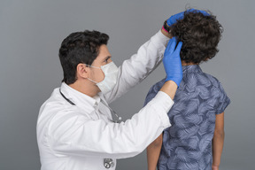 Médico examinando cabelo de menino