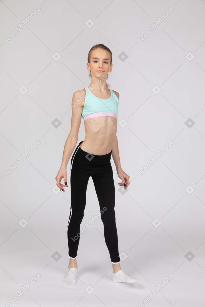 Three-quarter view of a teen girl in sportswear looking at camera while stretching back