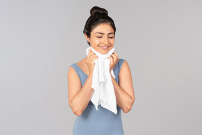 Giovane donna indiana con gli occhi chiusi asciugando il viso con un asciugamano