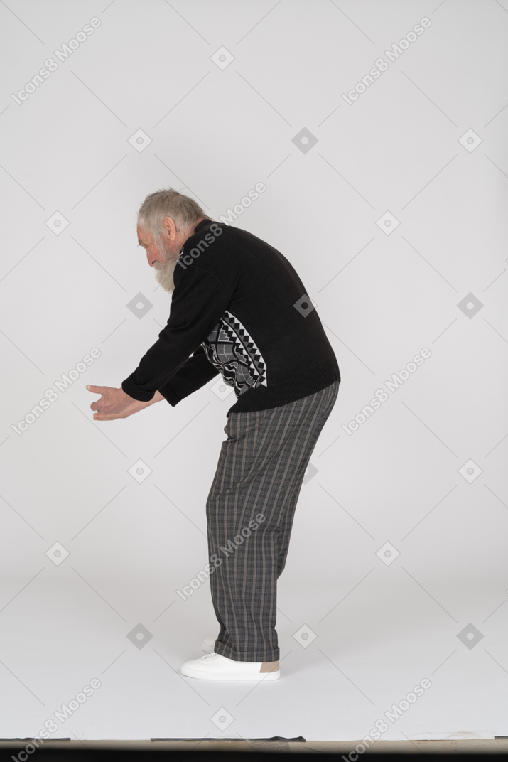 Side view of old man bending down with hands outstretched communicating