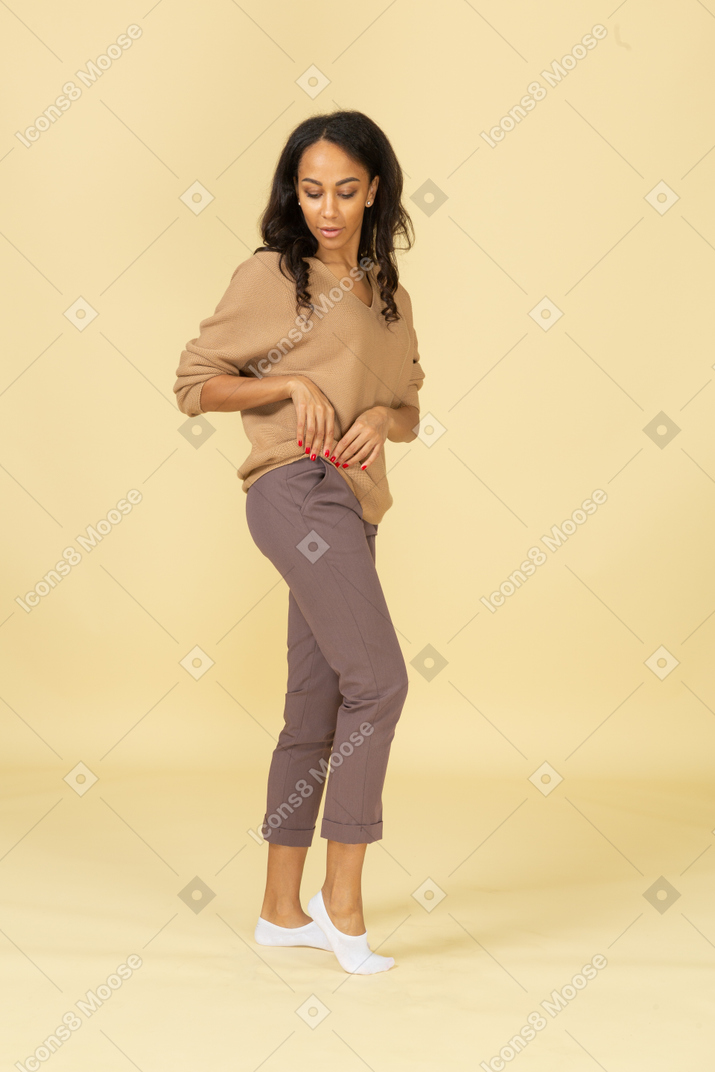 Vista lateral de uma jovem mulher de pele escura enrolando seu pulôver