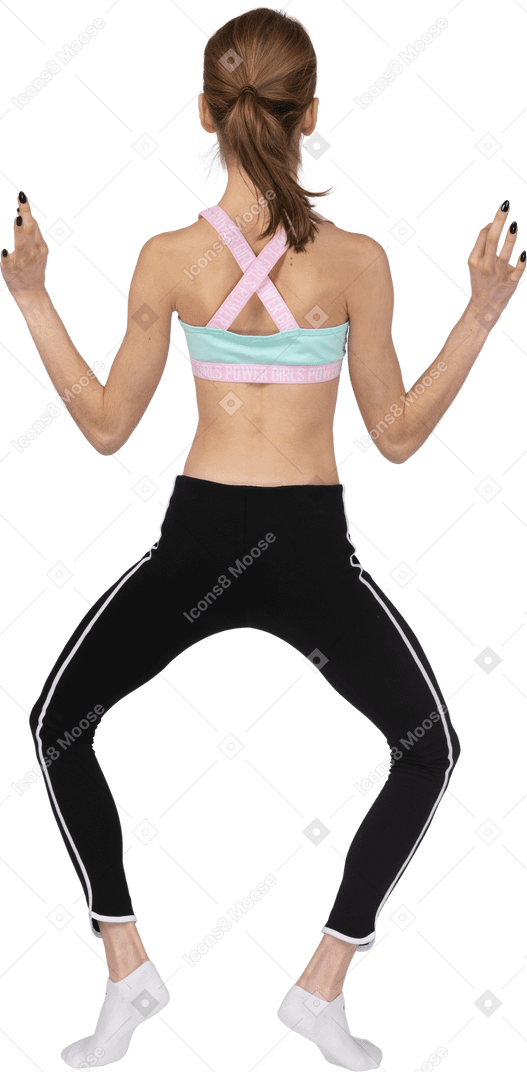 Back view of a teen girl in sportswear putting legs wide apart