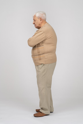 Vista lateral de um velho em roupas casuais em pé com os braços cruzados