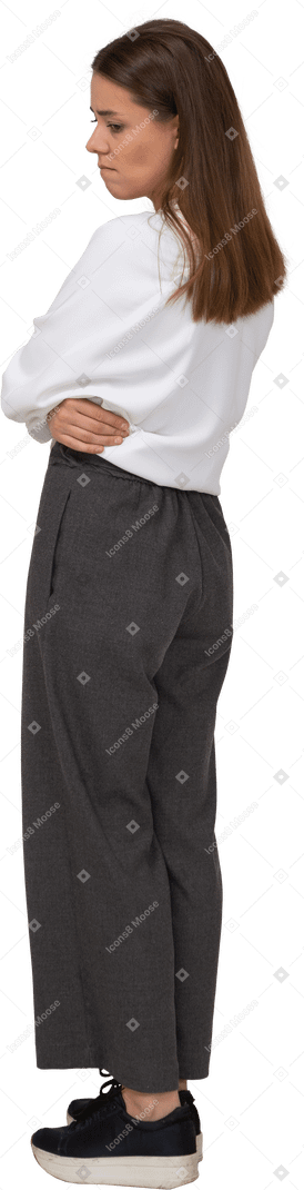 Vista posteriore di tre quarti di una giovane donna sconvolta in abiti da ufficio che mette le mani sulla pancia