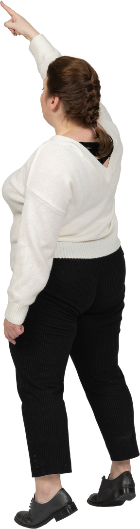 Rear view of a plus size woman in casual clothes standing with raised arm