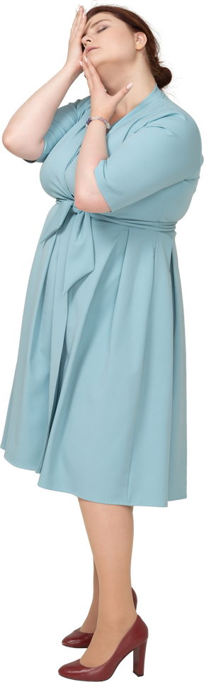 Вид сбоку женщины в синем платье позирует