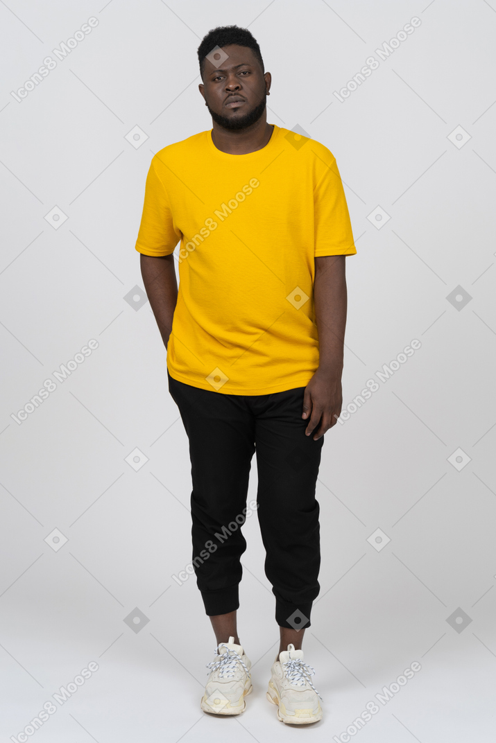 静止している黄色のtシャツを着た若い浅黒い肌の男の正面図