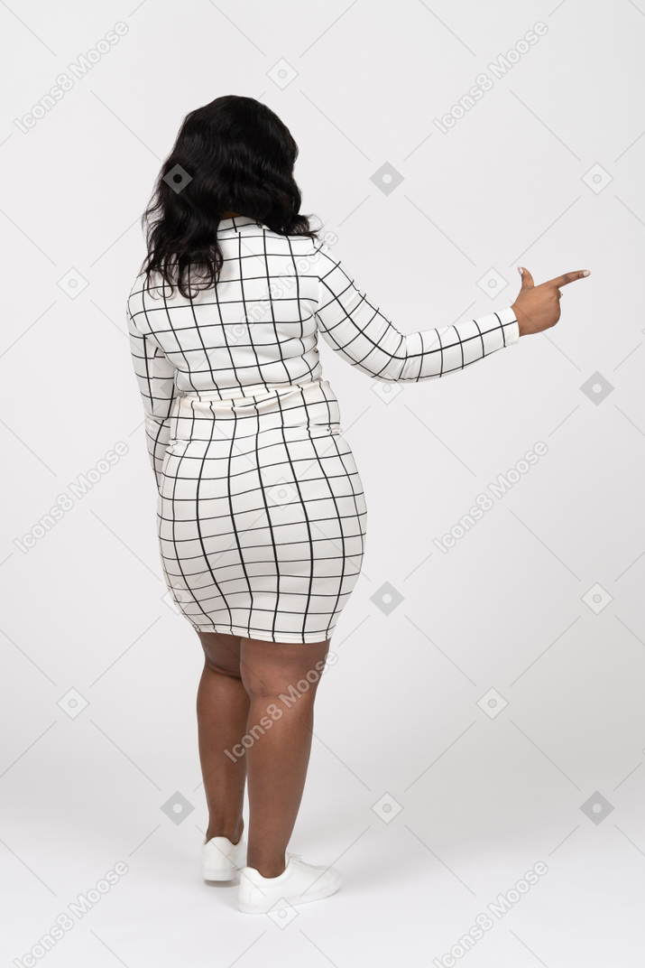 Vista posteriore di una giovane donna in abiti casual che indica con il dito
