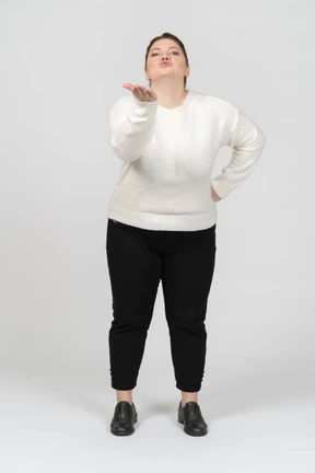 Plump woman in casual clothes blowing a kiss