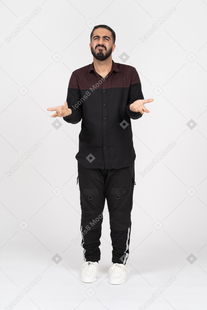 Young confused man spreading hands