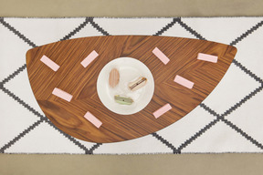 Pink marshmallows and eclairs on a wooden coffee table, top view